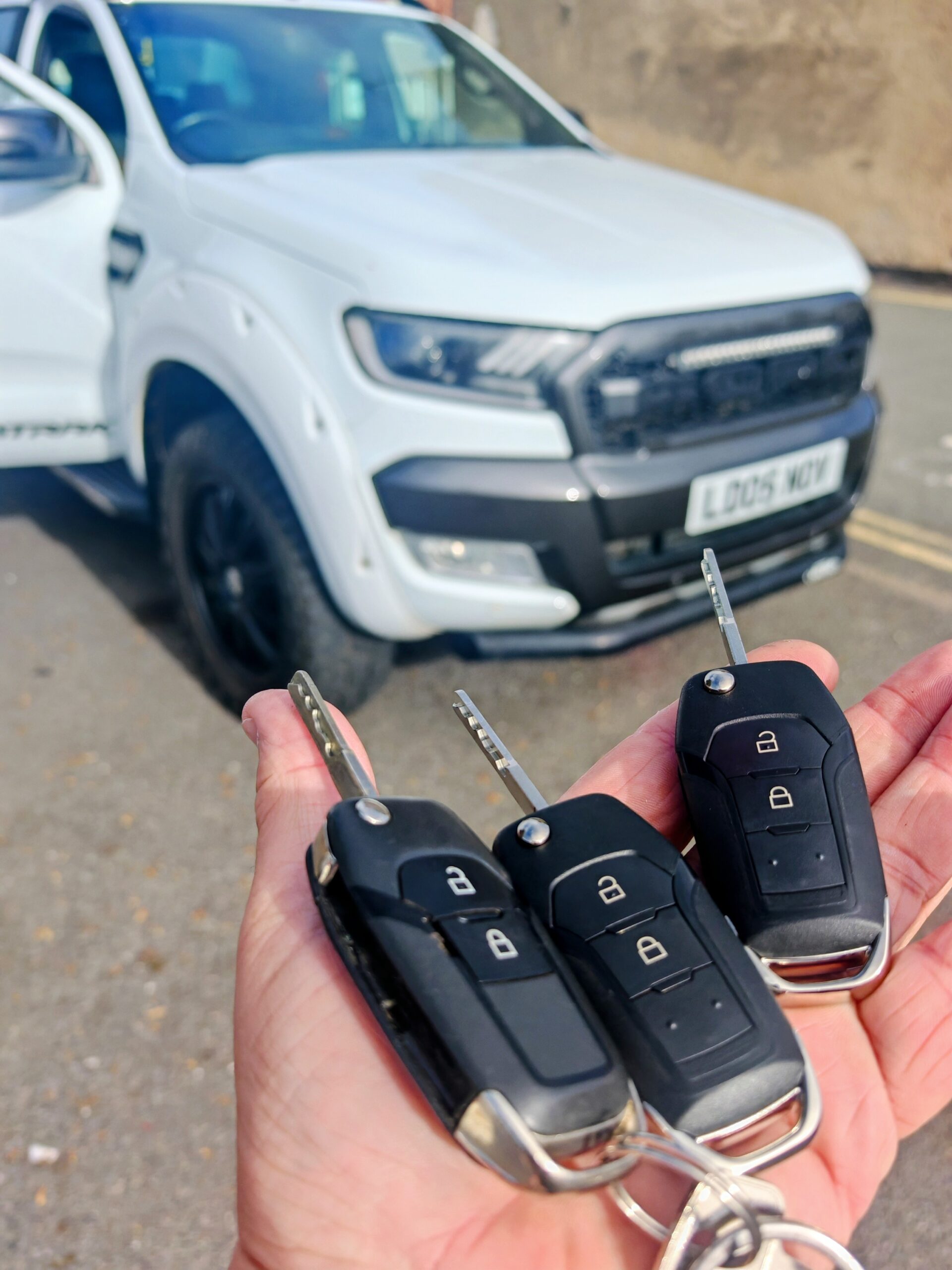 Two replacement car key fobs completed beside a vehicle